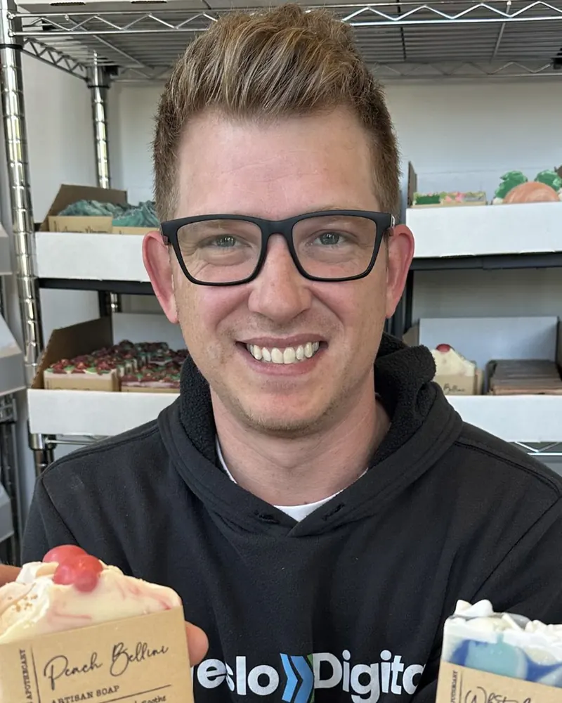 Brandon holding two bars of artisan soap in the Rose Marie Apothecary stockroom